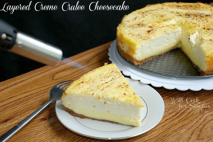 using cooking torch on slice of cheesecake with the rest of the cheesecake in the background on a cake platter