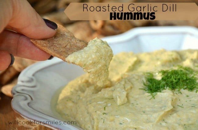 scooping out hummus from bowl with a bagel chip