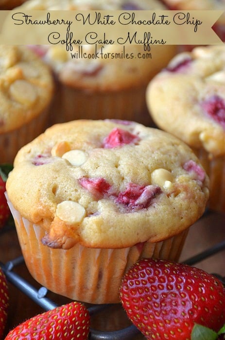 Strawberry white chocolate chip muffins on a cooling rack with strawberries on the table in front of it