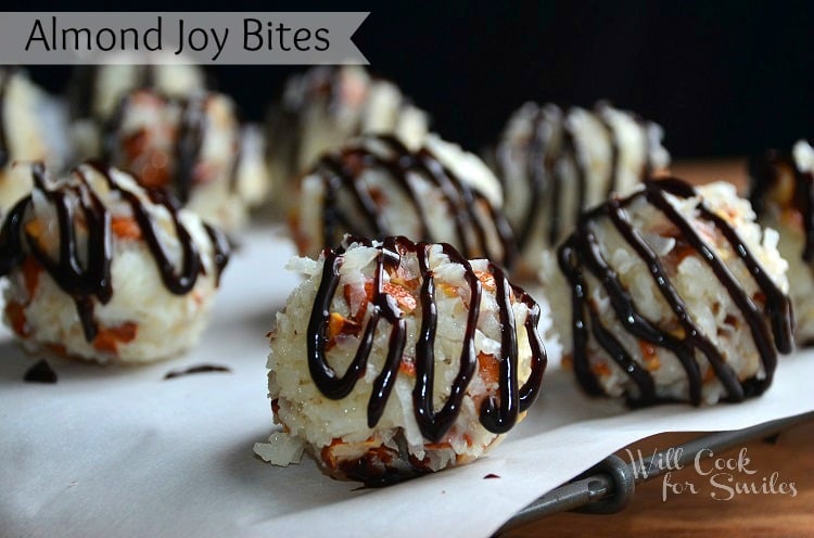 7 almond joy bites on wax paper resting on metal rack. Each bite drizzled with chocolate syrup