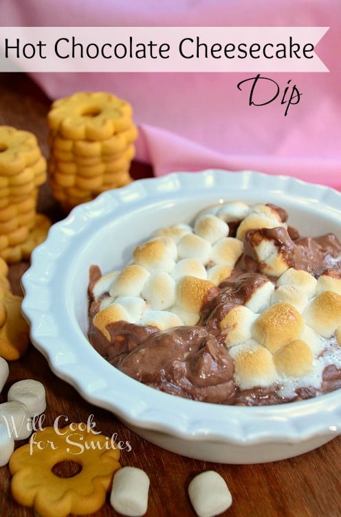 hot chocolate cheesecake dip with melted marshmallows on top and cookies to the left side