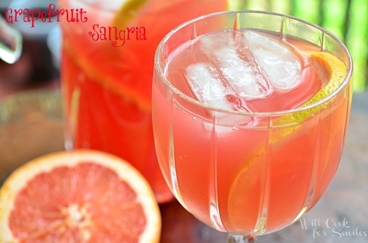 Grapefruit Sangria in a glass with a sliced grapefruit and a pitcher in the background