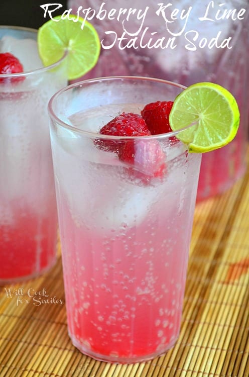 Raspberry Key Lime Italian Soda in a glass with lime and raspberries garnish