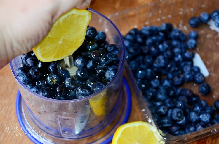 squeezing a lemon over Blueberries in a food processer