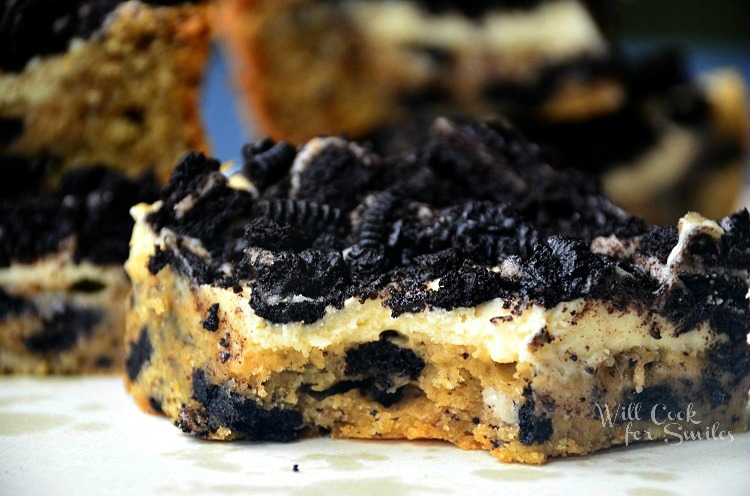 close up of oreo cheesecake bar on white plate with several more bars in background