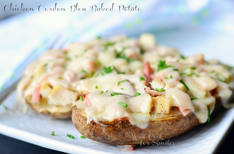 close up picture of 2 chicken cordon bleu baked potatoes on white plate topped with chopped parsley