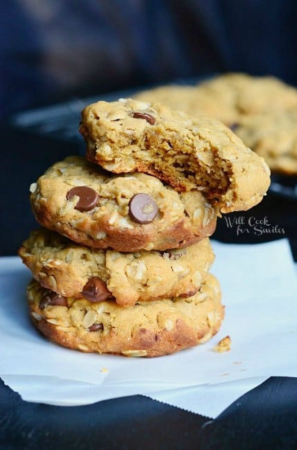 Peanut Butter Oatmeal Cookies with Chocolate Chips stacked up on a sheet of wax paper and a bite out of the top cookie