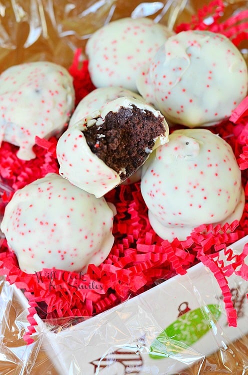 peppermint oreo bites in decorative gift box with shredded red paper with one bite in top