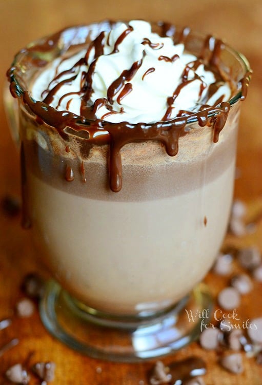 Adult Hot Chocolate in a clear glass mug with whip cream and chocolate sauce over the top