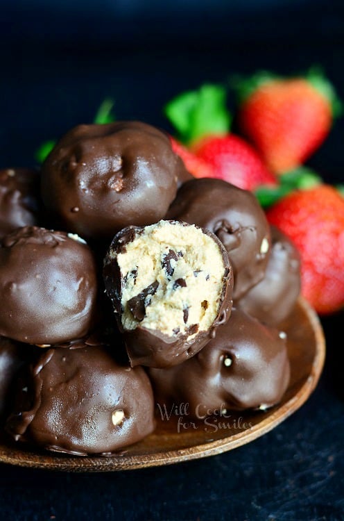 (No Bake) Chocolate Covered Peanut Butter Cheesecake Bites in a bowl with one with a bite out of it