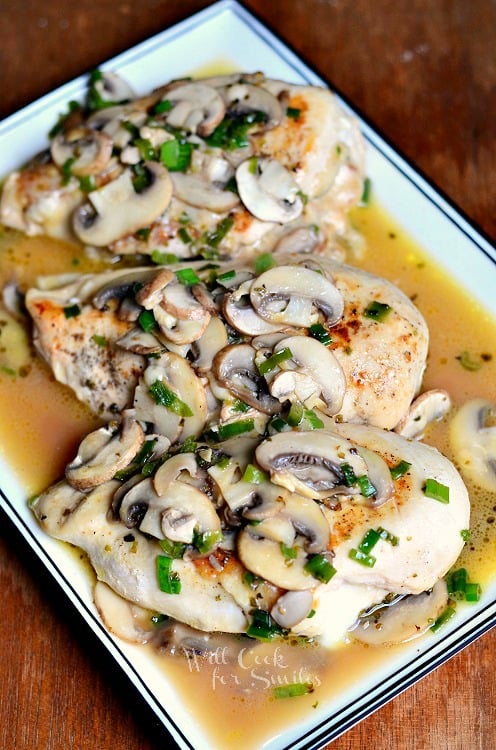 black and white decorative rectangular plate on a wood table with stuffed chicken marsala and a white napkin in the background