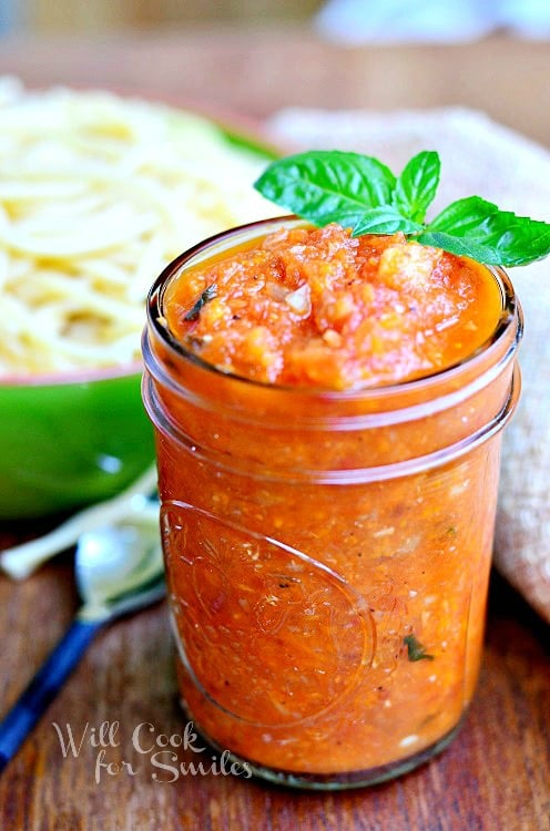 Homemade Marinara sauce in a jar with some basil on the side