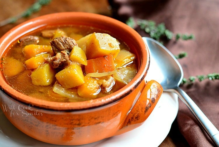 Slow Cooker Winter Squash Beef Stew in an orange bowl on a white plate
