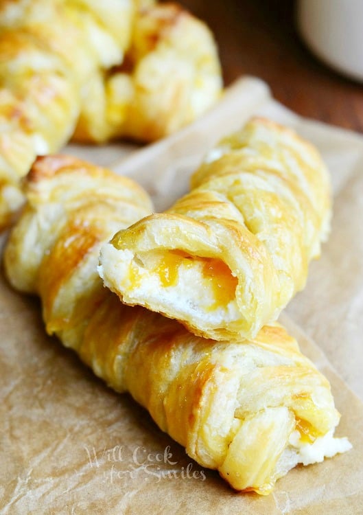 close up view of easy breakfast pastries stacked on tan wax paper with coffee mug in background to the right all on a wood table