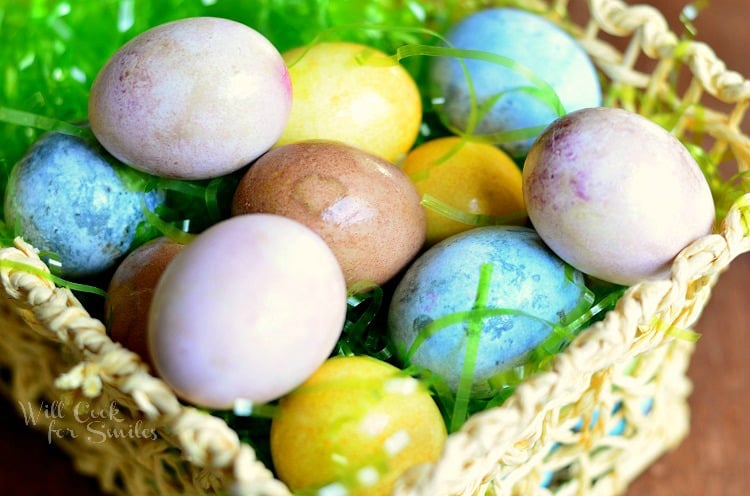 colored hard boiled eggs in an easter basket with green plastic easter grass