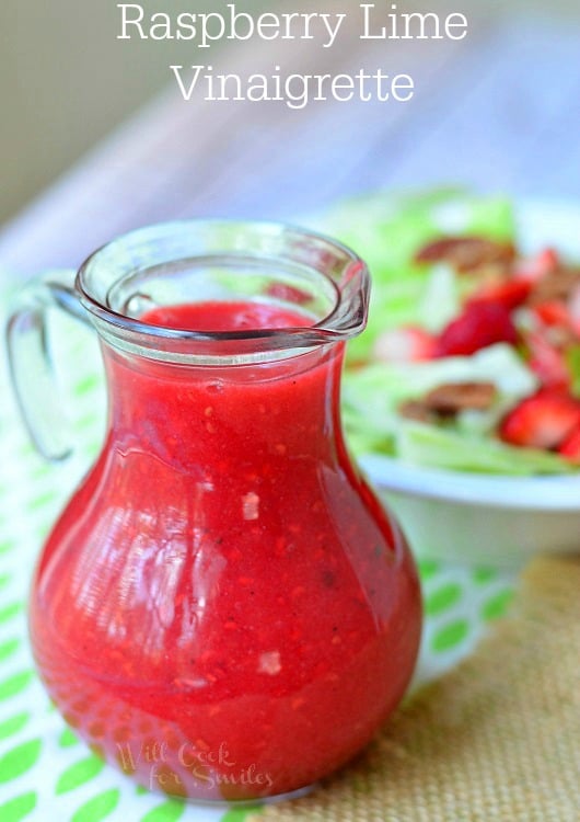 Raspberry Lime Vinaigrette dressing Cruet with salad above it in a bowl