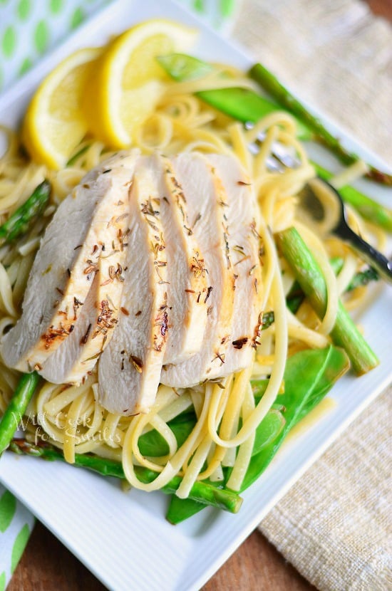 Linguine with Chicken, Asparagus and Snow Peas on a white square plate and with slices of lemon and a fork