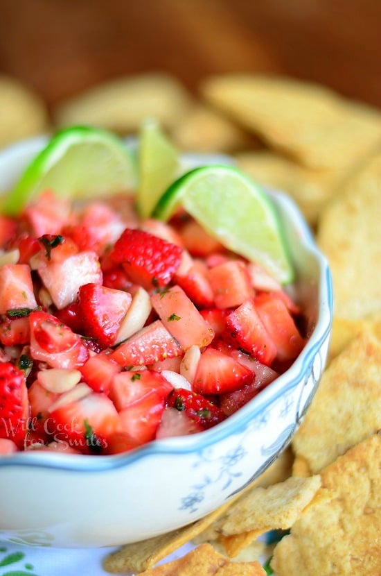 strawberry dessert salsa garnished with lime slices in a white bowl and surounded by chips
