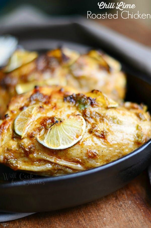 Chili Lime Roasted Chicken with limes on top in a cast iron skillet