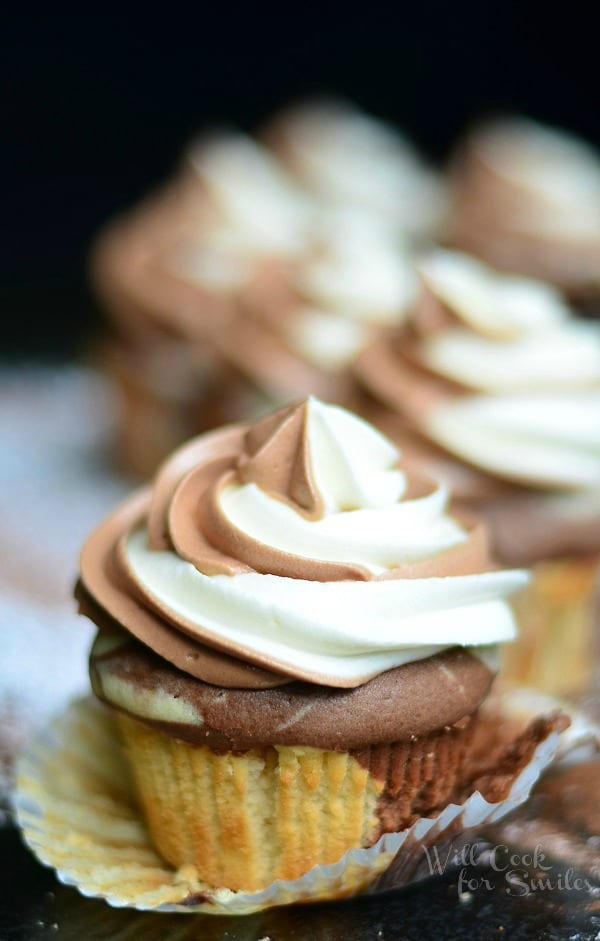Marble Cupcakes close up with cupcake liner pealed off on a black counter top with powdered sugar sprinkled on the counter