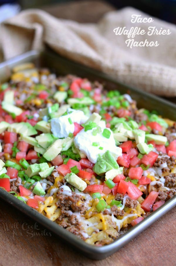 Taco Waffle Fries Nachos on a baking sheet with avocado, tomato, and cream cheese