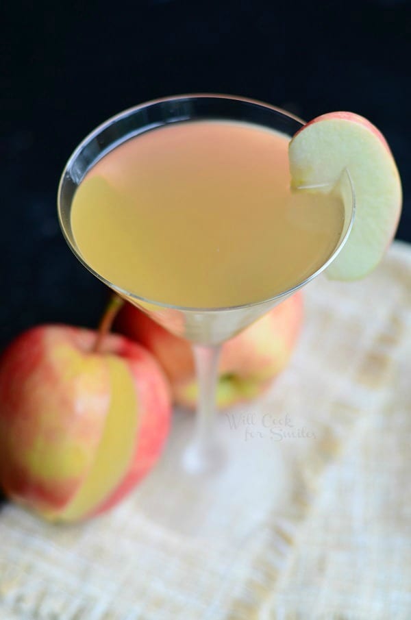 Apple Cider Martini in a martini glass with an apple slice as garnish and a apple on the table