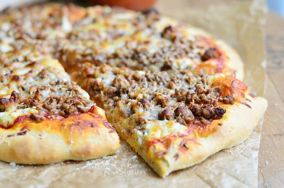 close up view of lasagna pizza on wax paper with one slice pulled from pizza pie