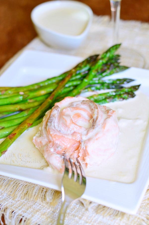 Salmon Rose with Creamy White Wine Sauce on a white plate with asparagus