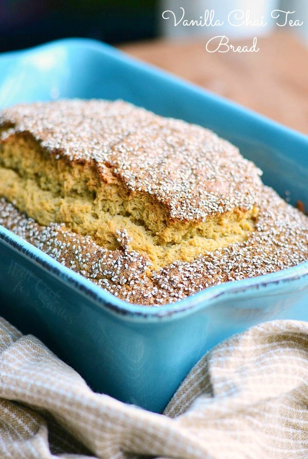 baked vanilla chai tea bread in a blue baking dish on a wooden table with a tan cloth below