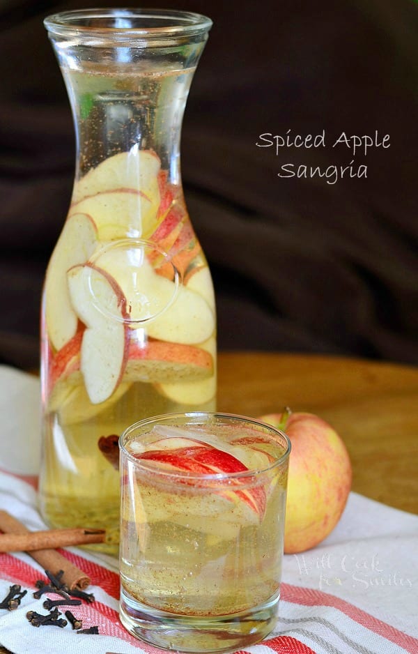 Spiced Apple Sangria in a pitcher with some poured in glass with apples