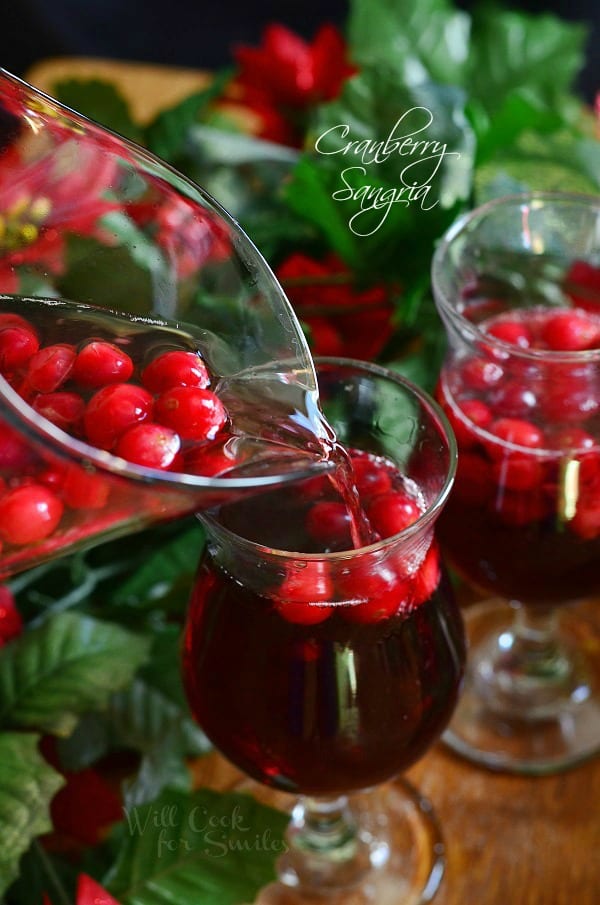 Cranberry Sangria being poured out of a pitcher into a glass