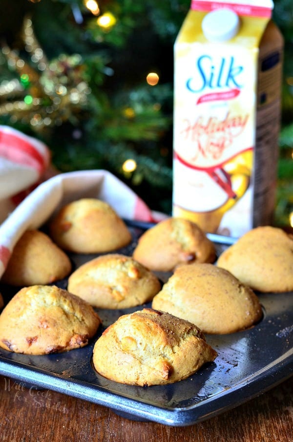White Chocolate Chip Eggnog Muffins in a muffin tin with silk holiday nog in the background