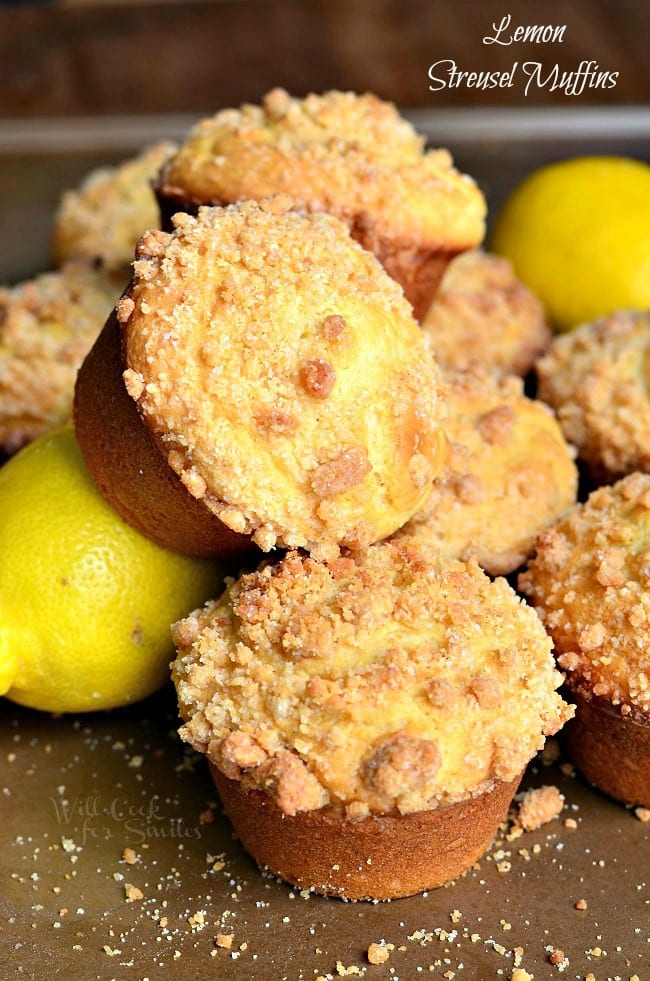 picture of lemon streusel muffins piled together with lemons at the bottom of the pileon a wooden table