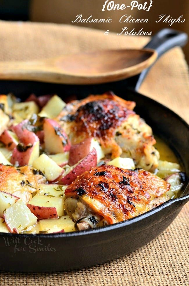 Balsamic Chicken Thighs & Potatoes in a cast iron skillet with a wood spoon over the top