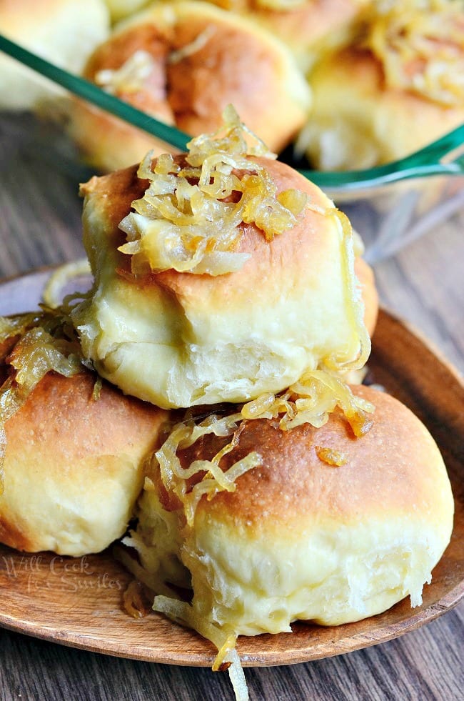 Caramelized Onion Dinner Rolls with onions on top on a wood plate