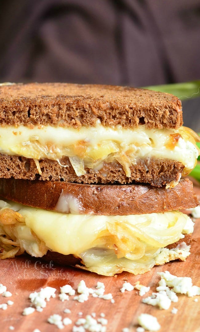 Gruyere and Caramelized Onion Grilled Cheese made with Gruyère cheese, blue cheese crumbles and caramelized onions. on a cutting board