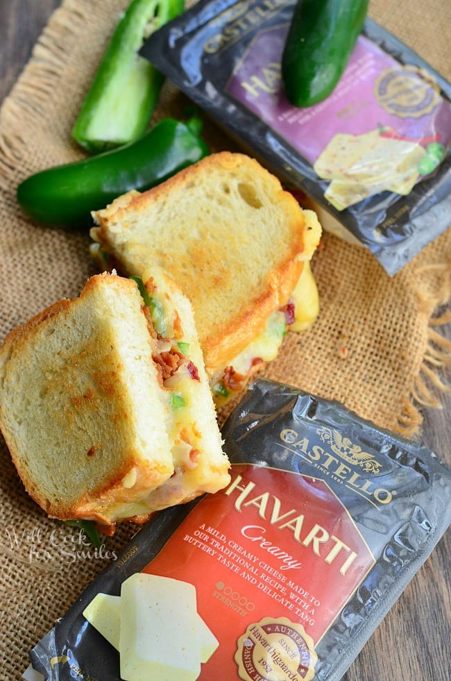 Jalapeno Popper Grilled Cheese loaded with gooey cheese, jalapenos and bacon cut in half with a jalapenos to the side and packages of cheese