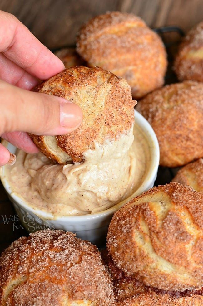 Snickerdoodle Pretzel Puff on a cooling wrack being dipped into bowl of cinnamon butter