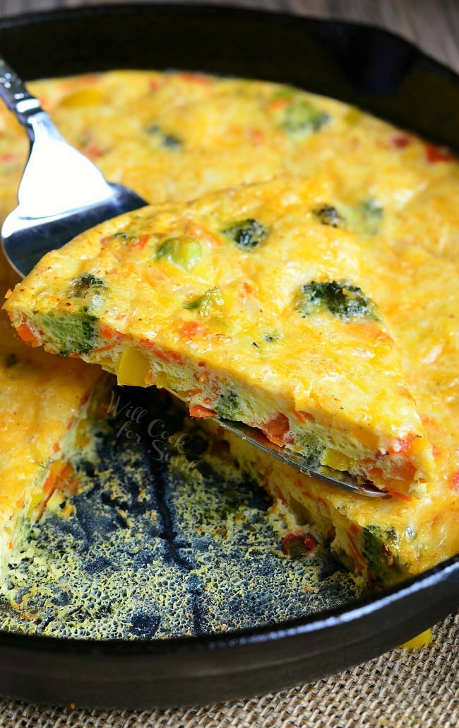 Fork lifting up one portion of vegetable and cheese overload breakfast bake over rest of dish