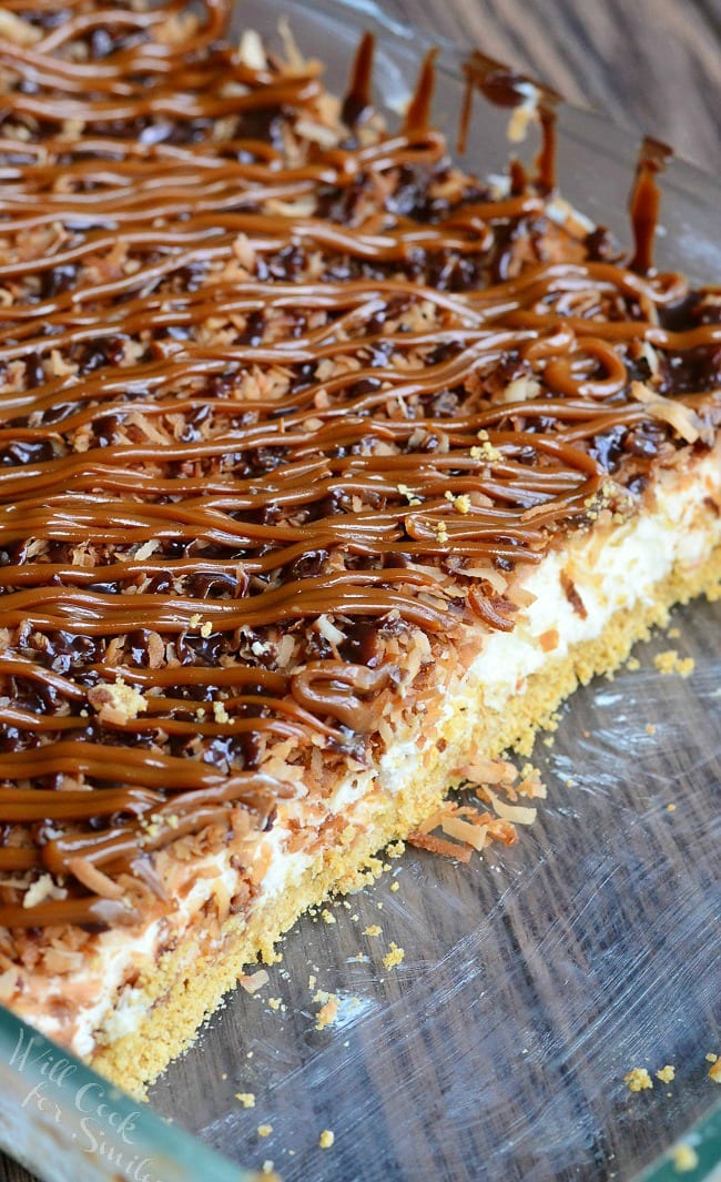 Samoas Cheesecake Bars with caramel and toasted coconut on top on a white plate