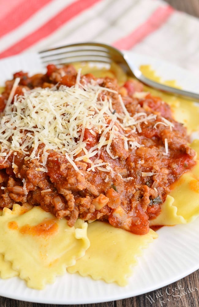 Ravioli with Meat Sauce with parmesan cheese on a white plate with a fork to the back