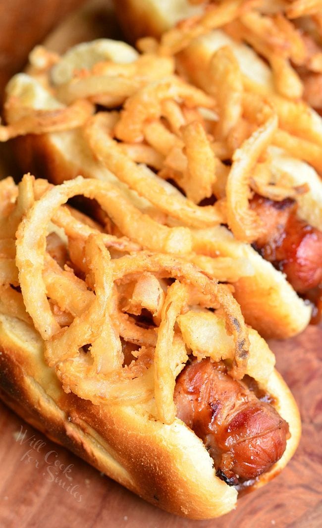 Fried Onions and Hot Dogs in a bun on a wood cutting board