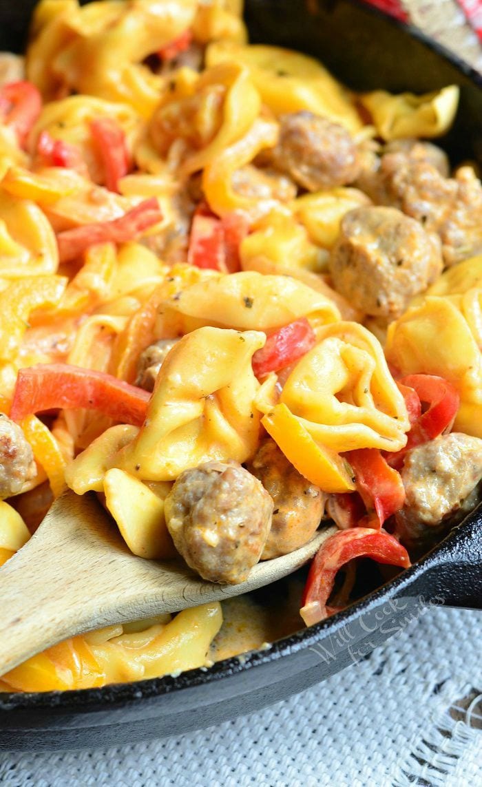 Sausage Peppers and Onion Tortellini Skillet with a wooden spoon on table