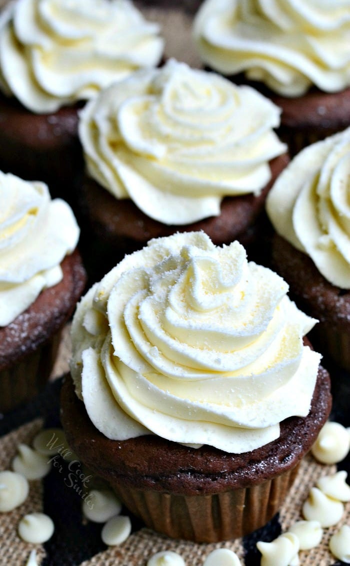 Double Chocolate Cupcakes with cream cheese cupcakes on a table with white chocolate chips around the it