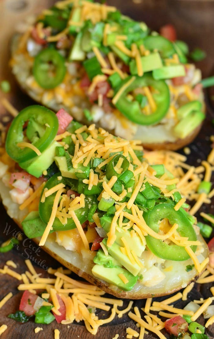 Top view Twice Baked Potatoes with cheese, green onions, jalapenos, and avocado