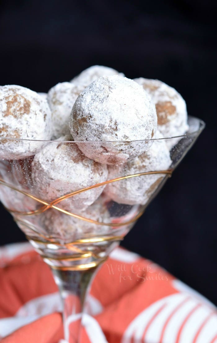 Decorative martini glass filled with pumpkin spice rum balls with a red and white cloth in the background