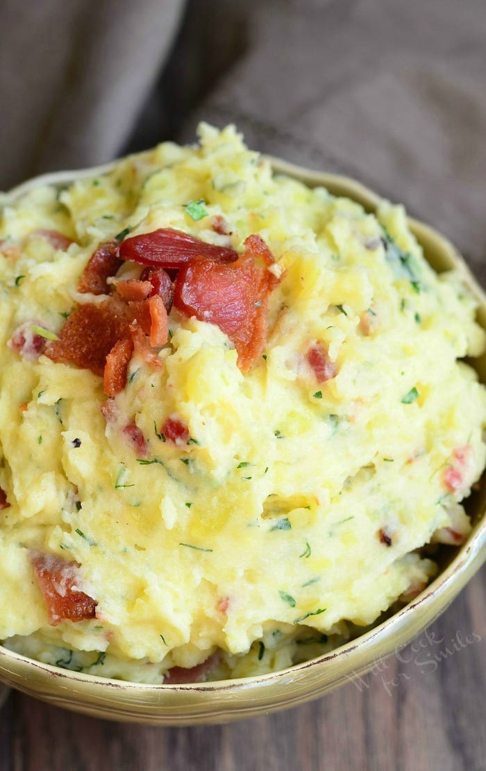 small decorative bowl filled with bacon and herbs creamy mashed potatoes on a wooden table
