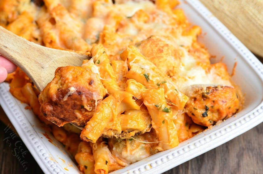 top view photo Chicken Meatball Baked Ziti in a white casserole dish with a wooden spoon