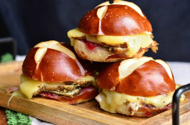 4 cranberry asiago turkey sliders stacked on a wooden cutting board viewed close up