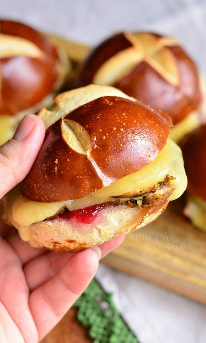 Holding a Cranberry Asiago Turkey Sliders that's on a pretzel bun